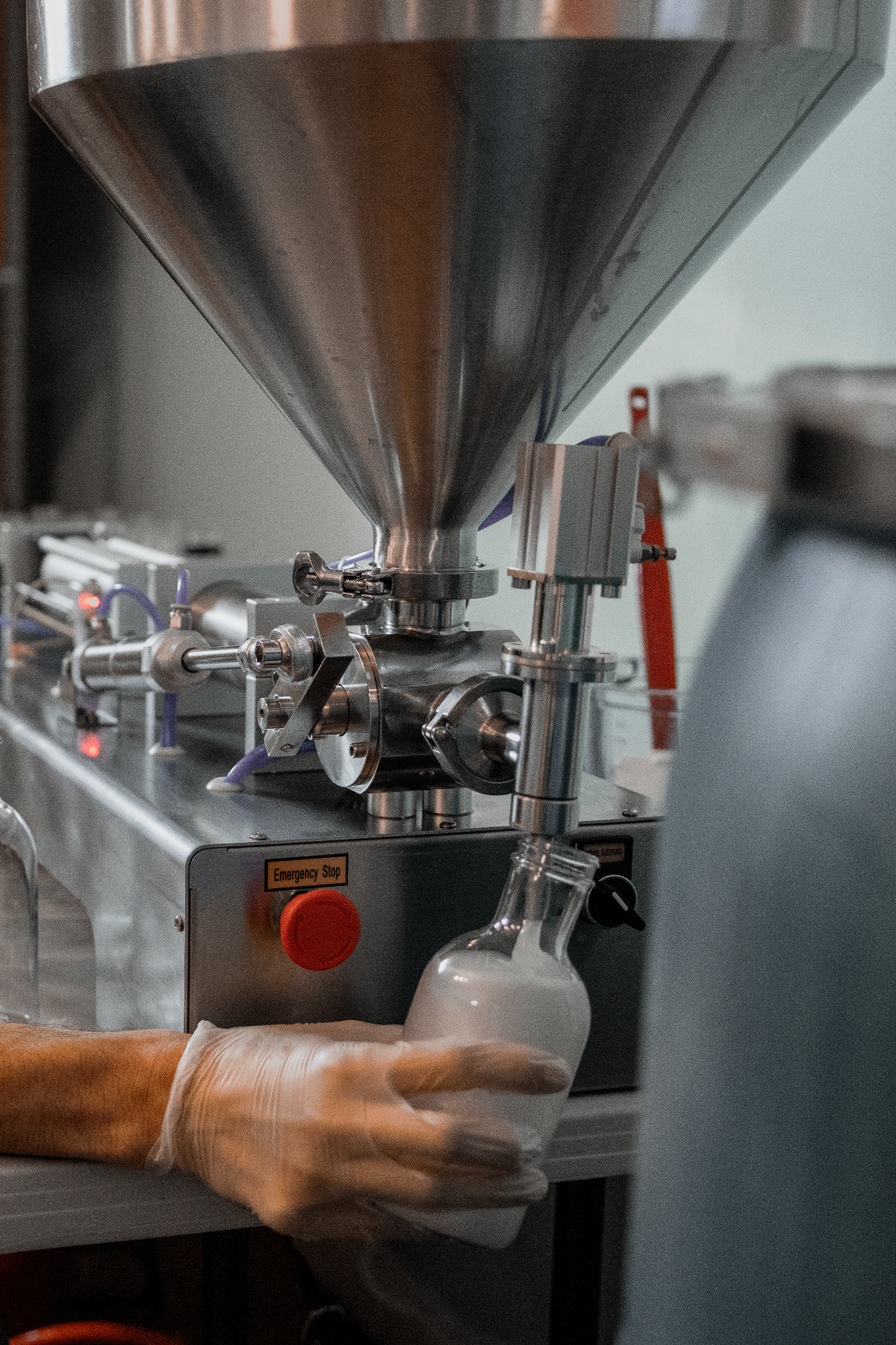 Person operating a machine that fills small bottles with a liquid.